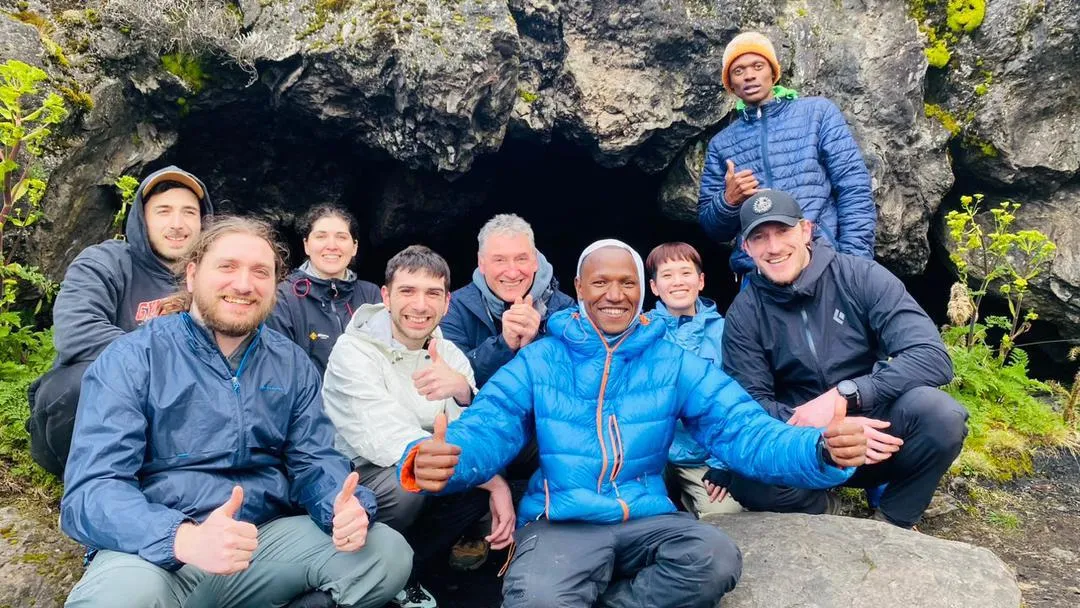 A happy group giving thumbs up with their guides at a lava cave on the mountain