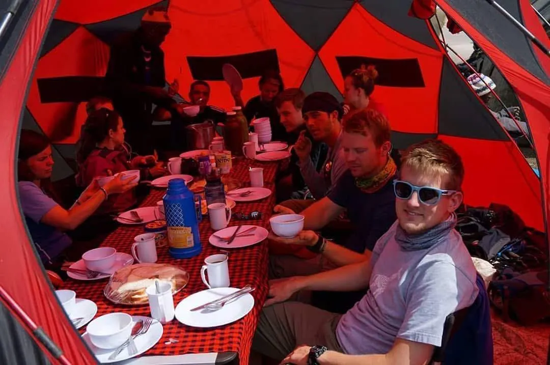 Trekkers sharing a meal together around the table in the mess tent