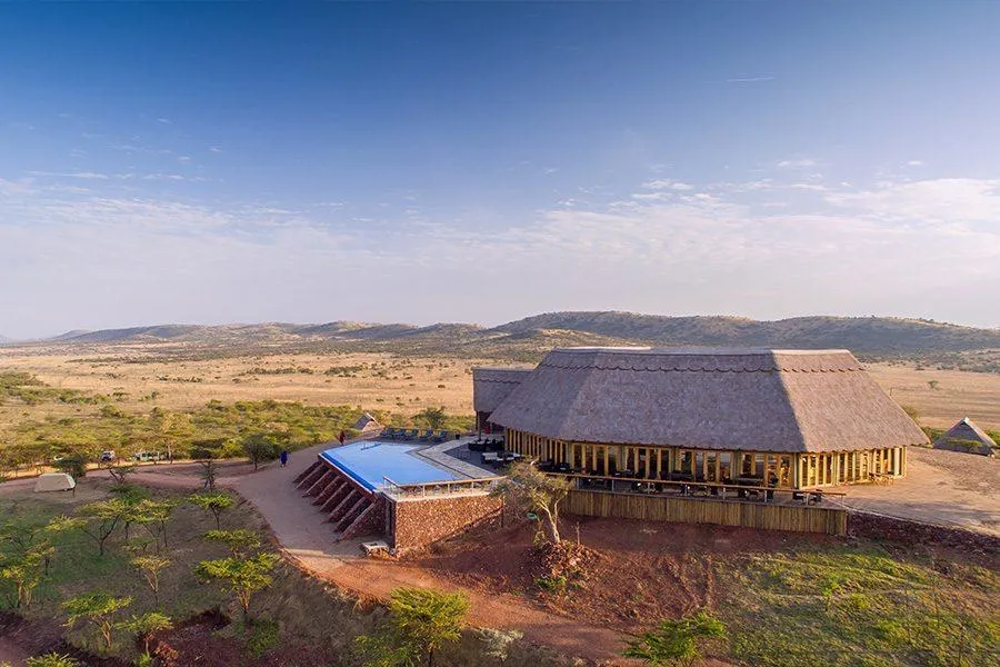 A thatched safari lodge with a pool overlooking the savanna