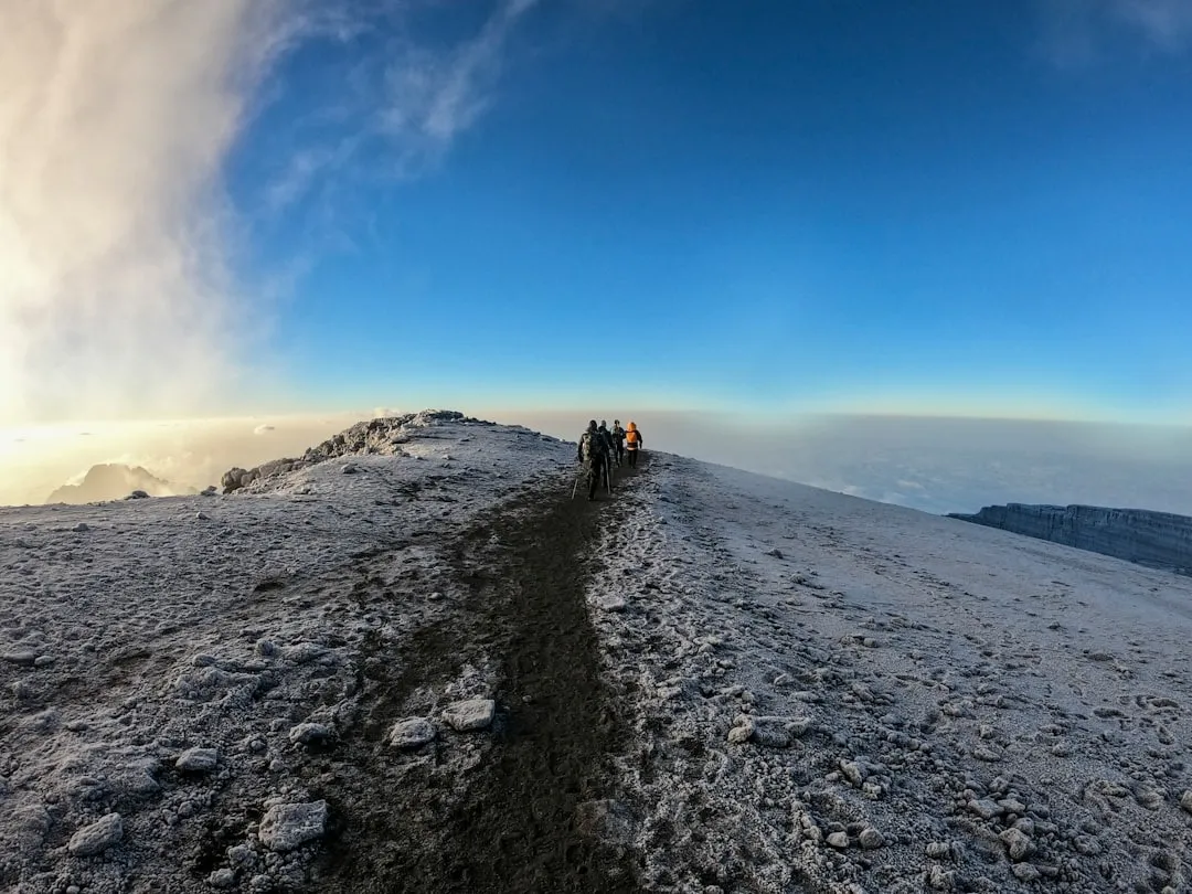Climbers crossing the snowy summit ridge of Kilimanjaro above the clouds